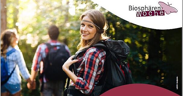 Plakat der Biosphärenwoche, eine Frau in Wanderkleidung dreht sich um und lacht in die Kamera