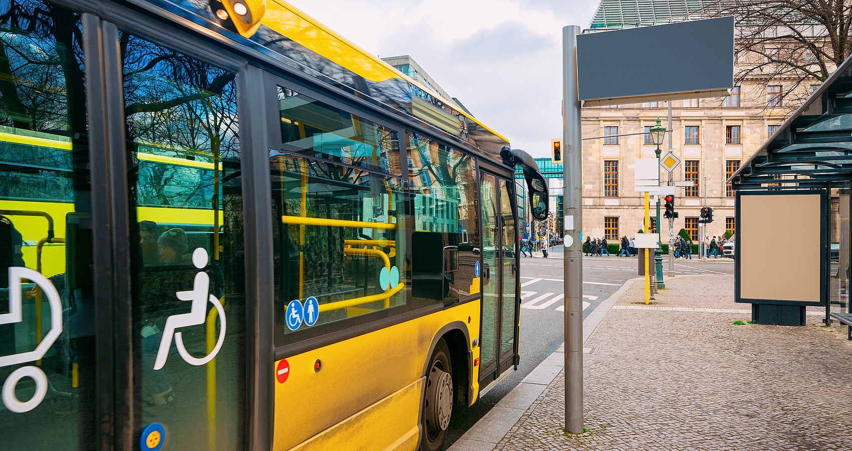 Gelber Bus mit barrierefreiem Einstieg hält an einer Bushaltestelle