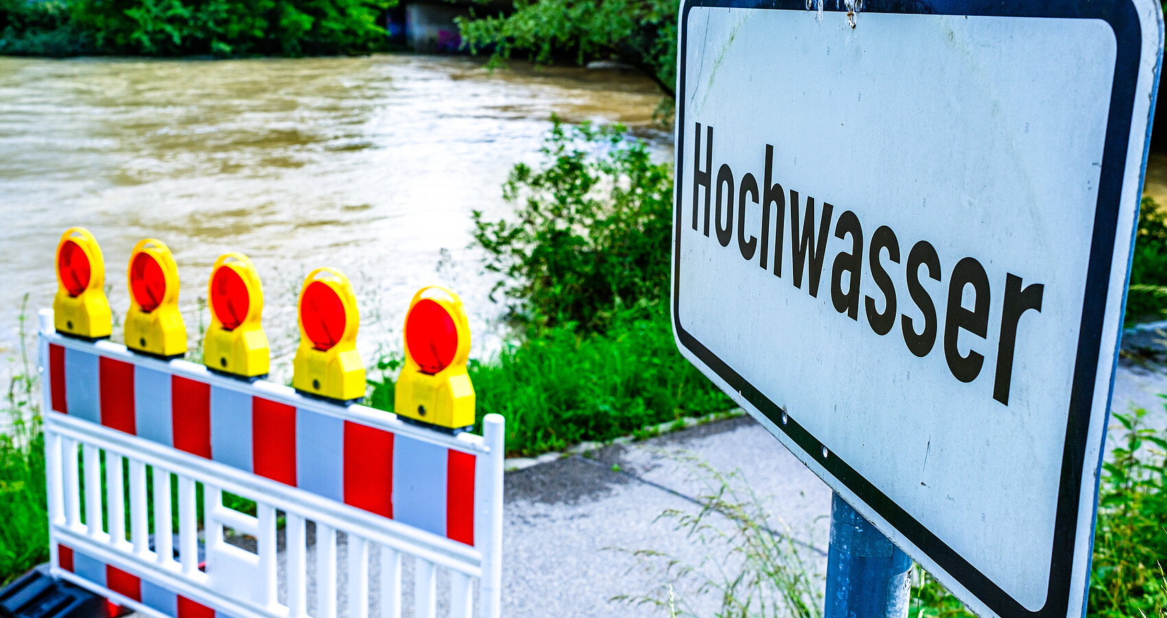 Bild zeigt Absperrung vor einem hochwasserführenden Fluss