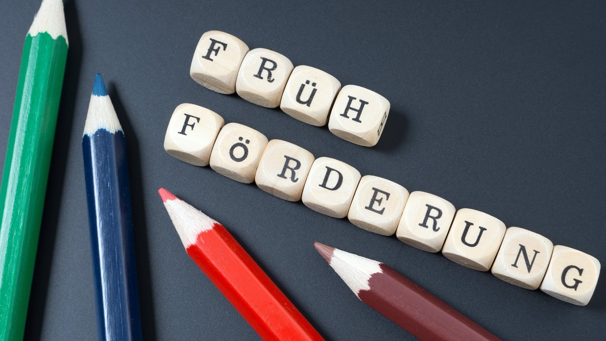Bleistifte und Würfel mit dem Wort Frühförderung