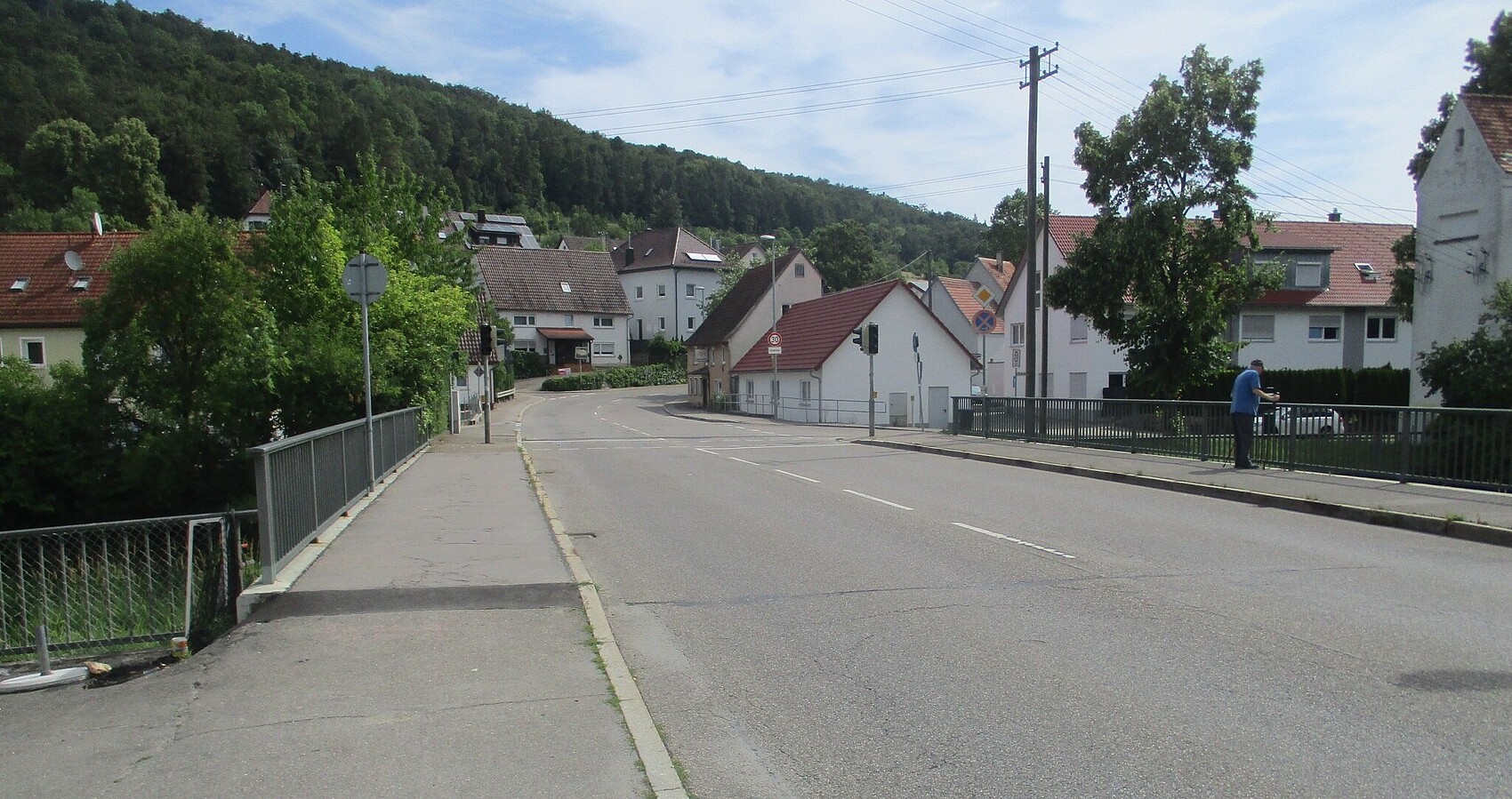Das Foto zeigt die Ortsdurchfahrt von Gerhausen; mehrere Häuser und eine Brücke; im Hintergrund Wald