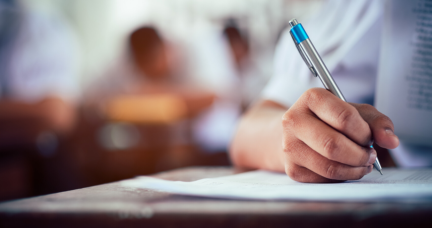 Das Foto zeigt eine Person an einem Schreibtisch mit einem Stift in der Hand