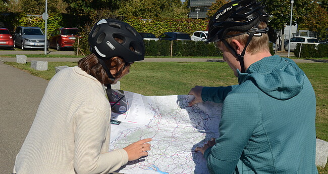 Zwei Personen auf dem Fahrrad betrachten gemeinsam eine Karte