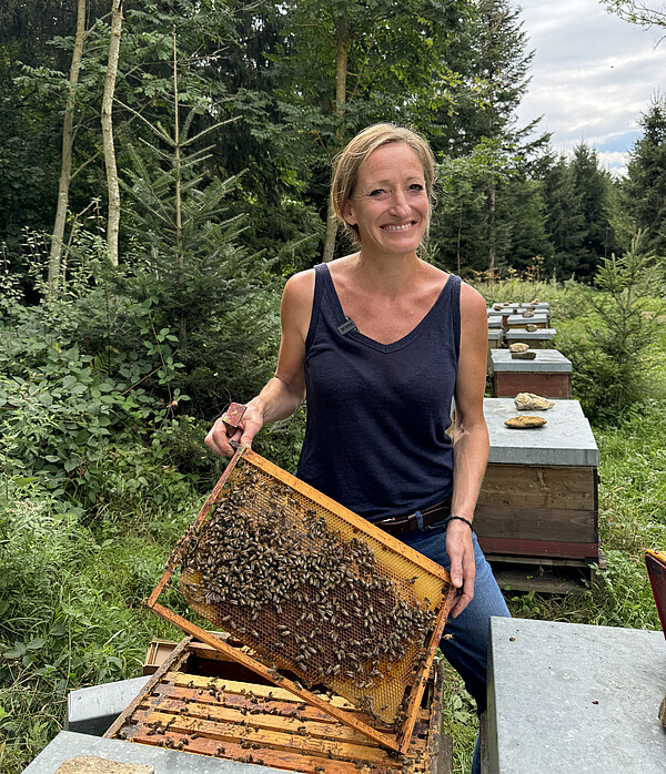 Die Imkerin Dr. Eva Frey zeigt eine Wabe mit Bienen.