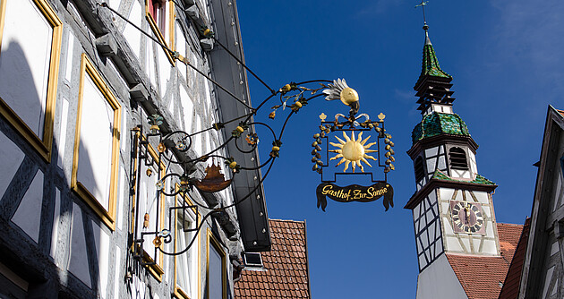Das Bild zeigt ein Schild eines Gasthauses im Ortskern einer Stadt