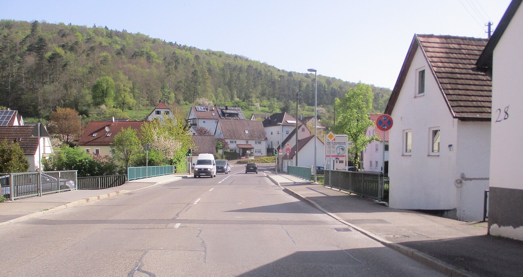 Das Foto zeigt die Brücke über den Neumühlkanal in Blaubeuren-Gerhausen. Mehrere Wohnhäuser und im Hintergrund ein Wald.