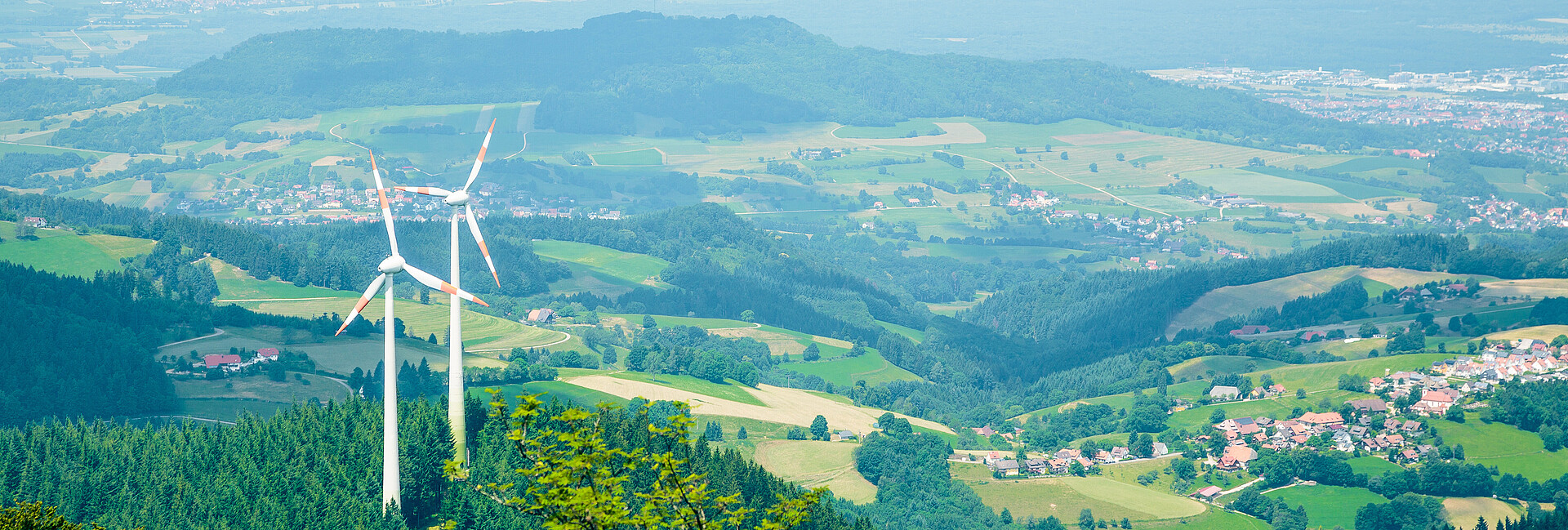 Man blickt von oben auf zwei Windenergieanlagen, die im Wald auf dem Berg Schauinsland stehen.