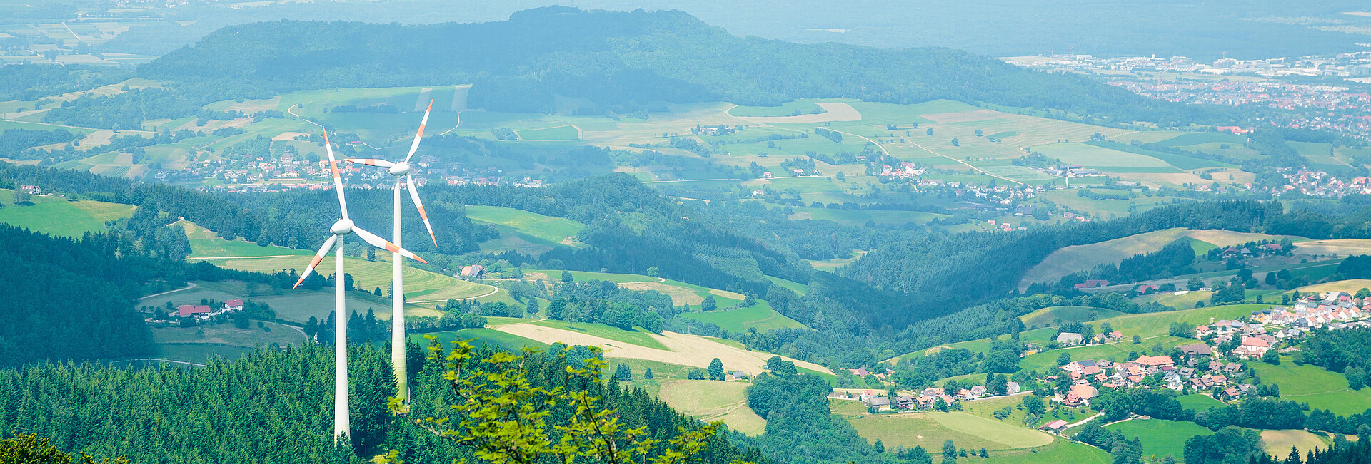 Man blickt von oben auf zwei Windenergieanlagen, die im Wald auf dem Berg Schauinsland stehen.