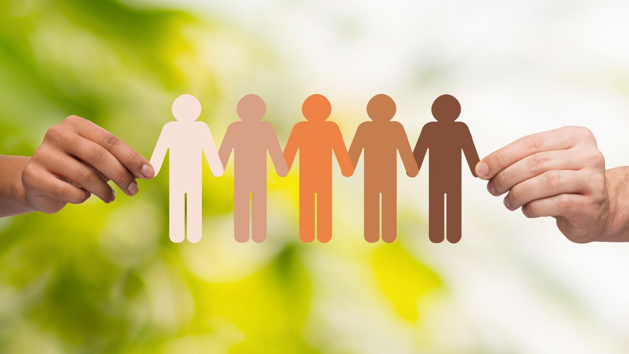 Zwei Hände halten eine Papier-Menschenkette