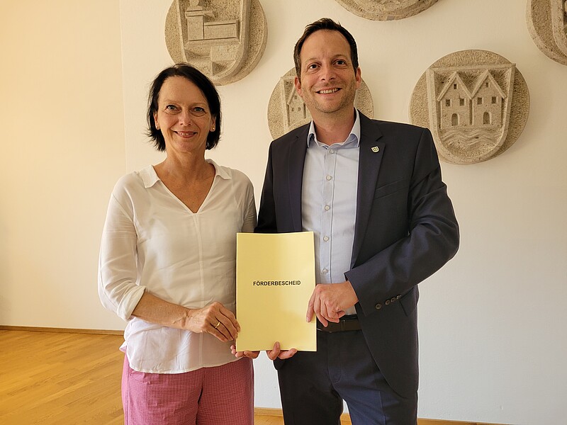 Regierungspräsidentin Susanne Bay übergibt Dr. Sebastian Kampe, Bürgermeister der Gemeinde Rot am See, den Förderbescheid in Höhe von rund rund 5,8 Millionen Euro