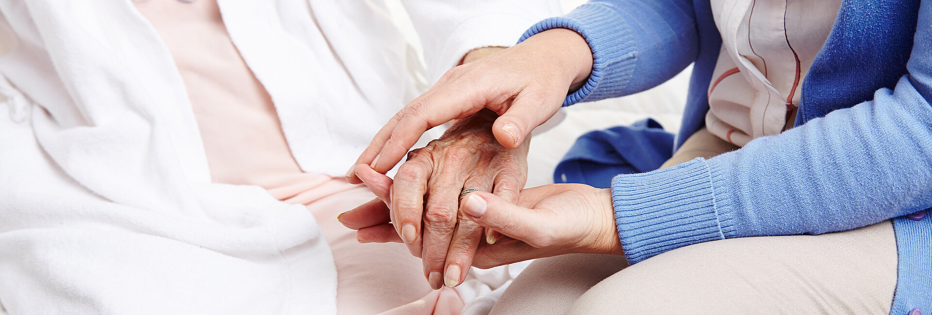 Frau hält Hand einer Seniorin