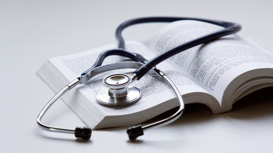 Bild zeigt Stethoskop auf einem medizinischen Lehrbuch liegend