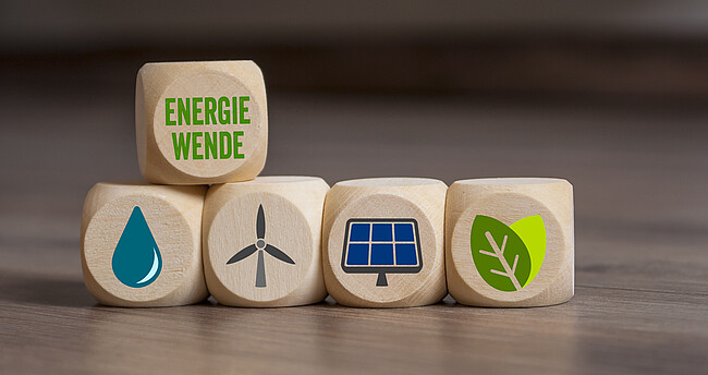 Symbolbild Energiewende; verschiedene Würfel liegen auf dem Tisch und zeigen Symbole für Windktaft, Wasserkraft, Solarenergie, Erdwärme und Biomasse
