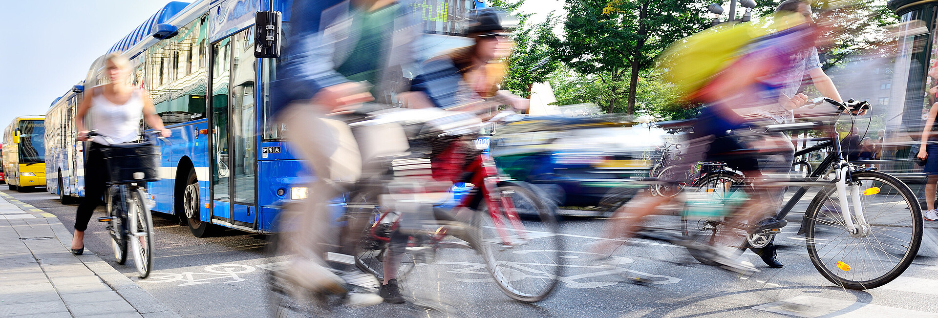 Fahrradfahrerinnen und -fahrer vor Bus und Auto